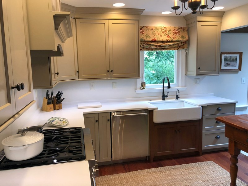 Painted upper kitchen cabinets above a white farmhouse sink with dark wood lower cabinetry.