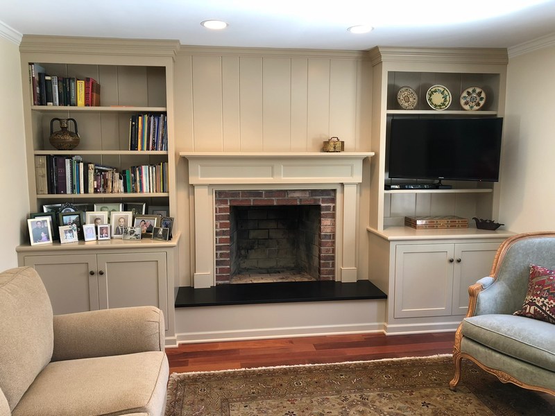 Painted built-in bookshelves and lower cabinets flanking a fireplace, with a television on the right.