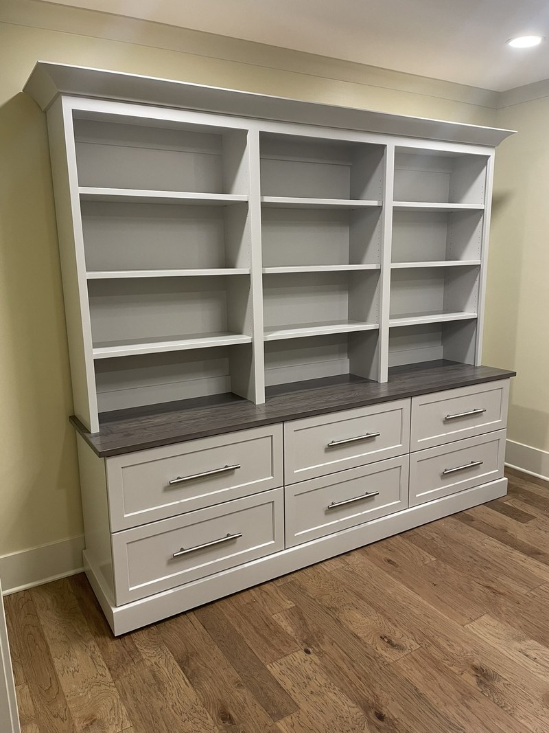 Freestanding painted storage unit with open upper shelves, a dark counter and six lower drawers.