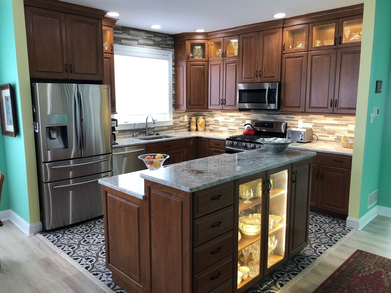 Dark wood kitchen cabinets with a central island and illuminated glass-front display doors.