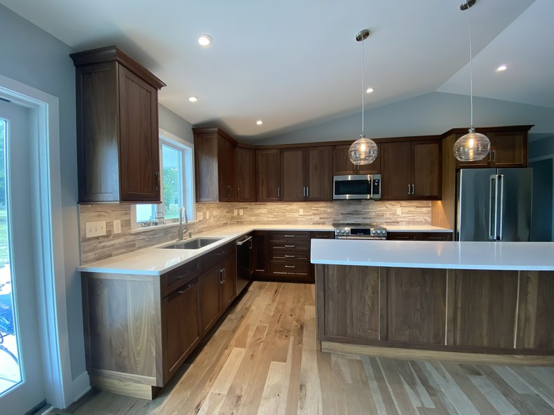 Wood kitchen cabinets with a light countertop, peninsula and stainless steel range and refrigerator.