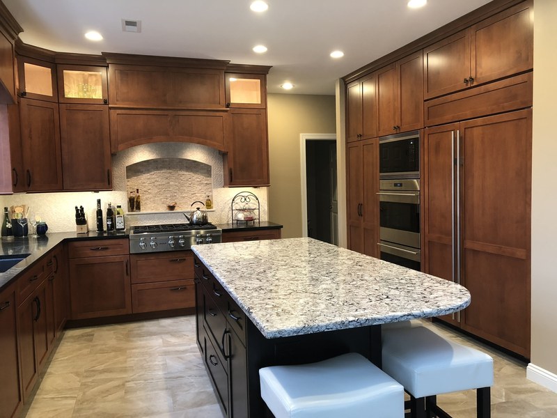 Dark wood kitchen cabinets around a range, with a curved backsplash opening and a large island.